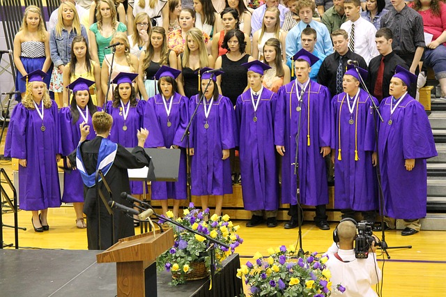 A group of graduates dressed in purple cap and cape stand on stage